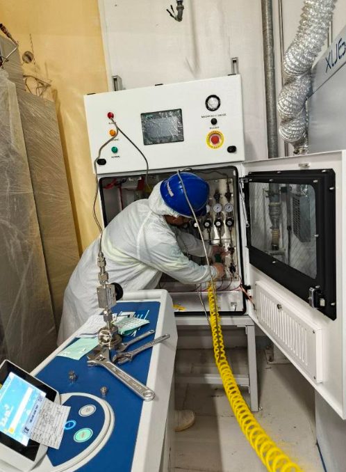 Technician performing a helium leak test on a valve manifold box gas stick